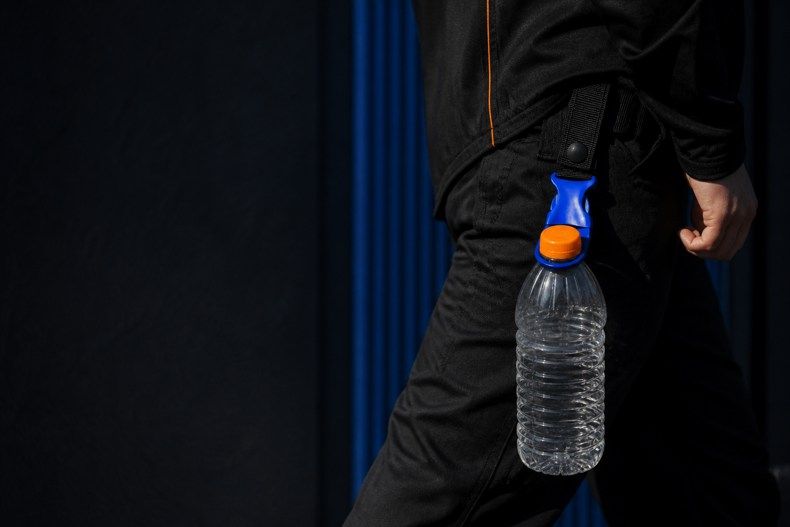NEAR Link 01 carrying an orange-capped bottle from black technical trousers